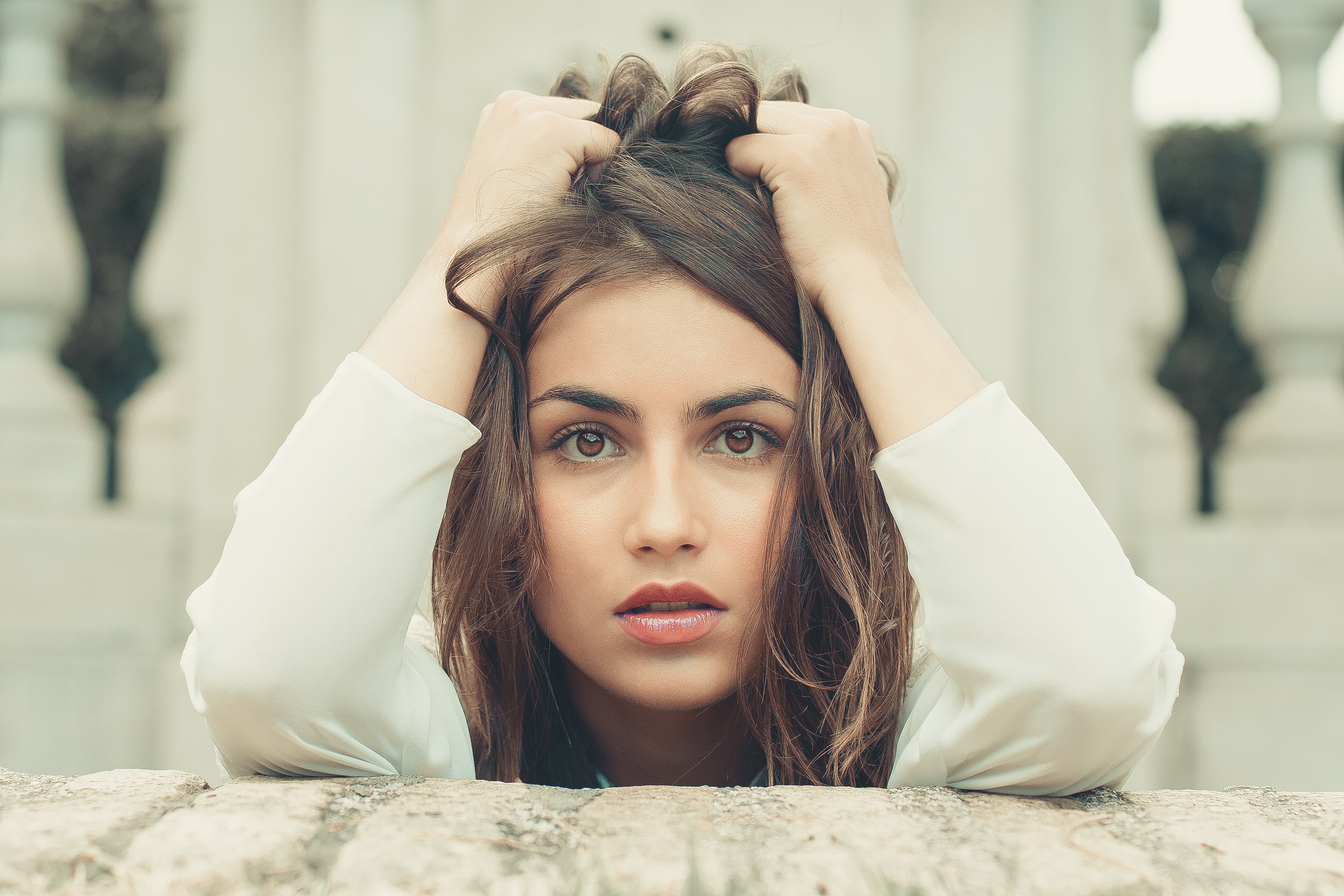 A woman is staring at the camera with an expression of dispair on her face. Her hands are running through her hair as if frustrated.