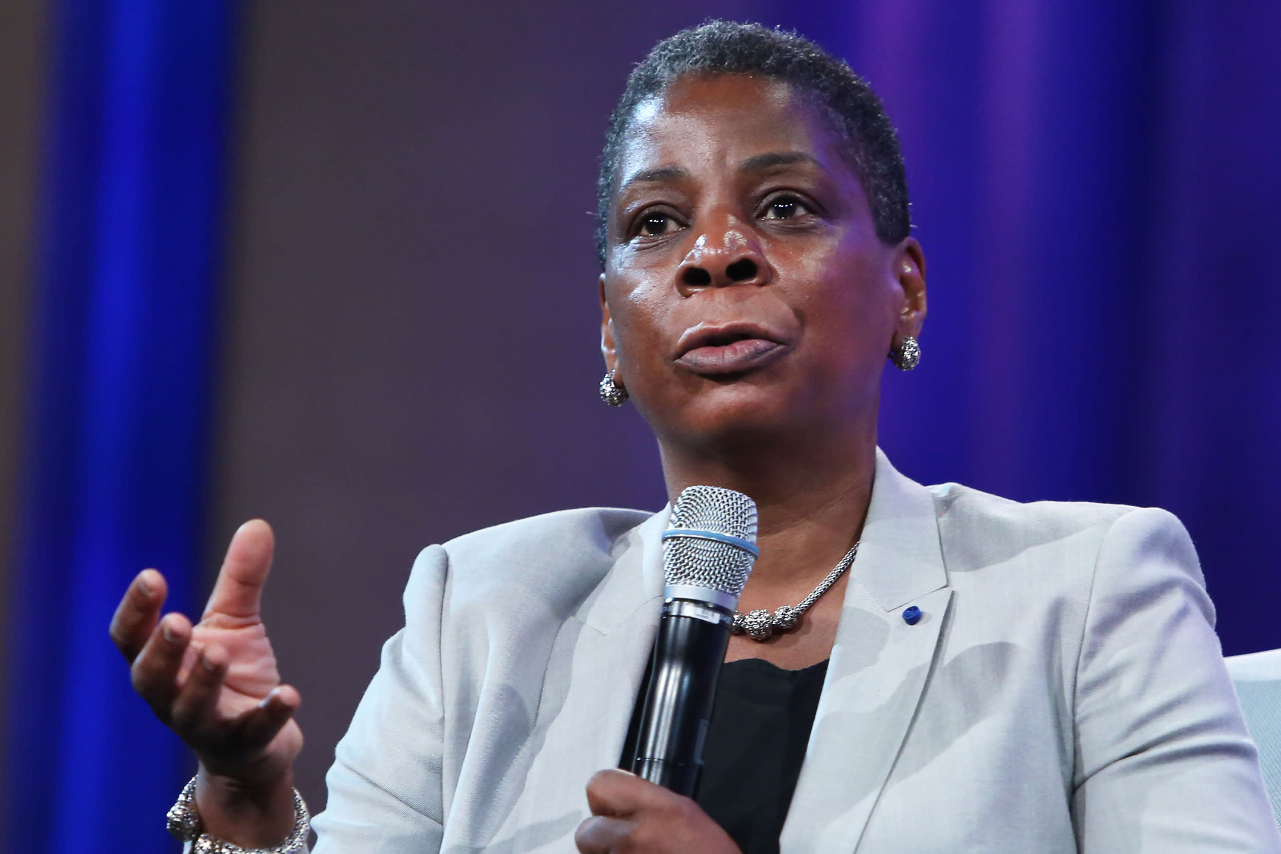 A photo of successful black business woman Ursula Burns, who was the CEO of Xerox. It looks as if she is giving a speech, and she has a microphone held underneath her mouth as if presenting to an audience.