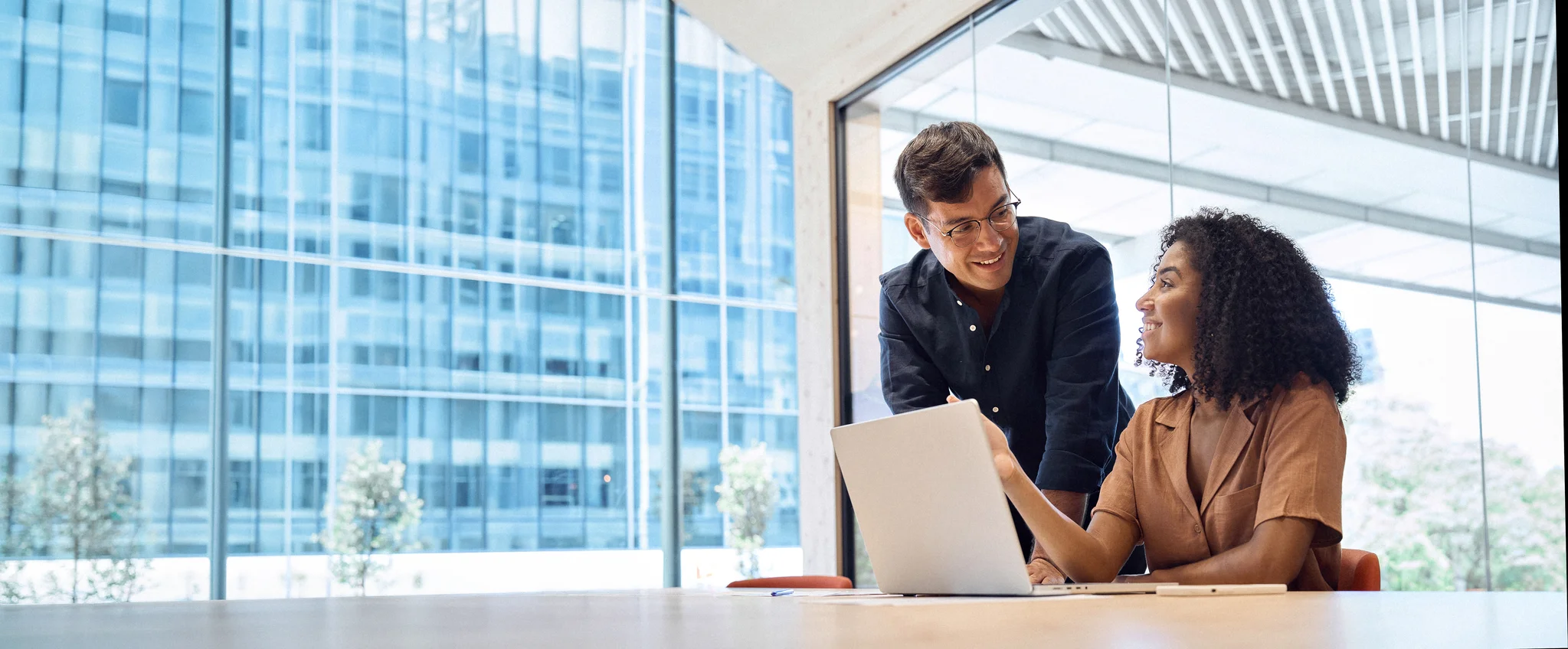 Business team two happy busy diverse young professional executives working together on computer at work