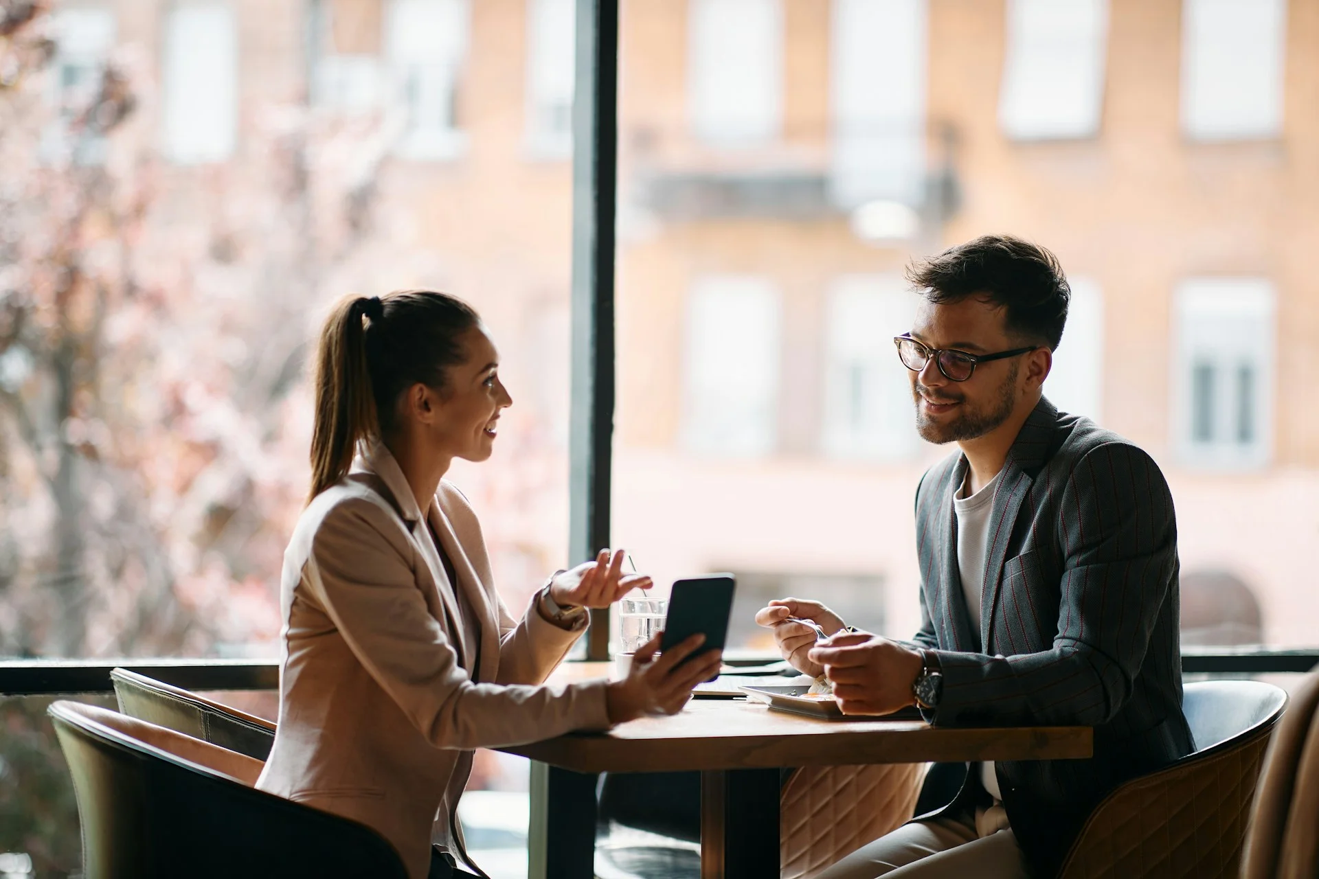 young-businesswoman-showing-something-on-smart-phone-to-her-colleague-while-being-in-a-cafe-focus-is-on-businessman-