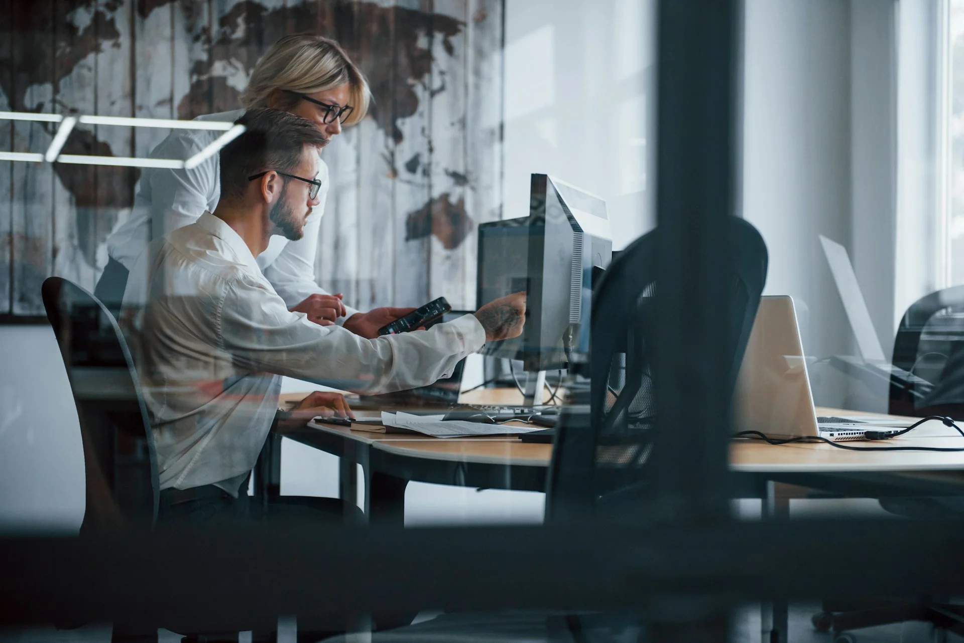 view-through-the-glass-two-stockbrokers-in-formal-clothes-works-in-the-office-with-financial-market-