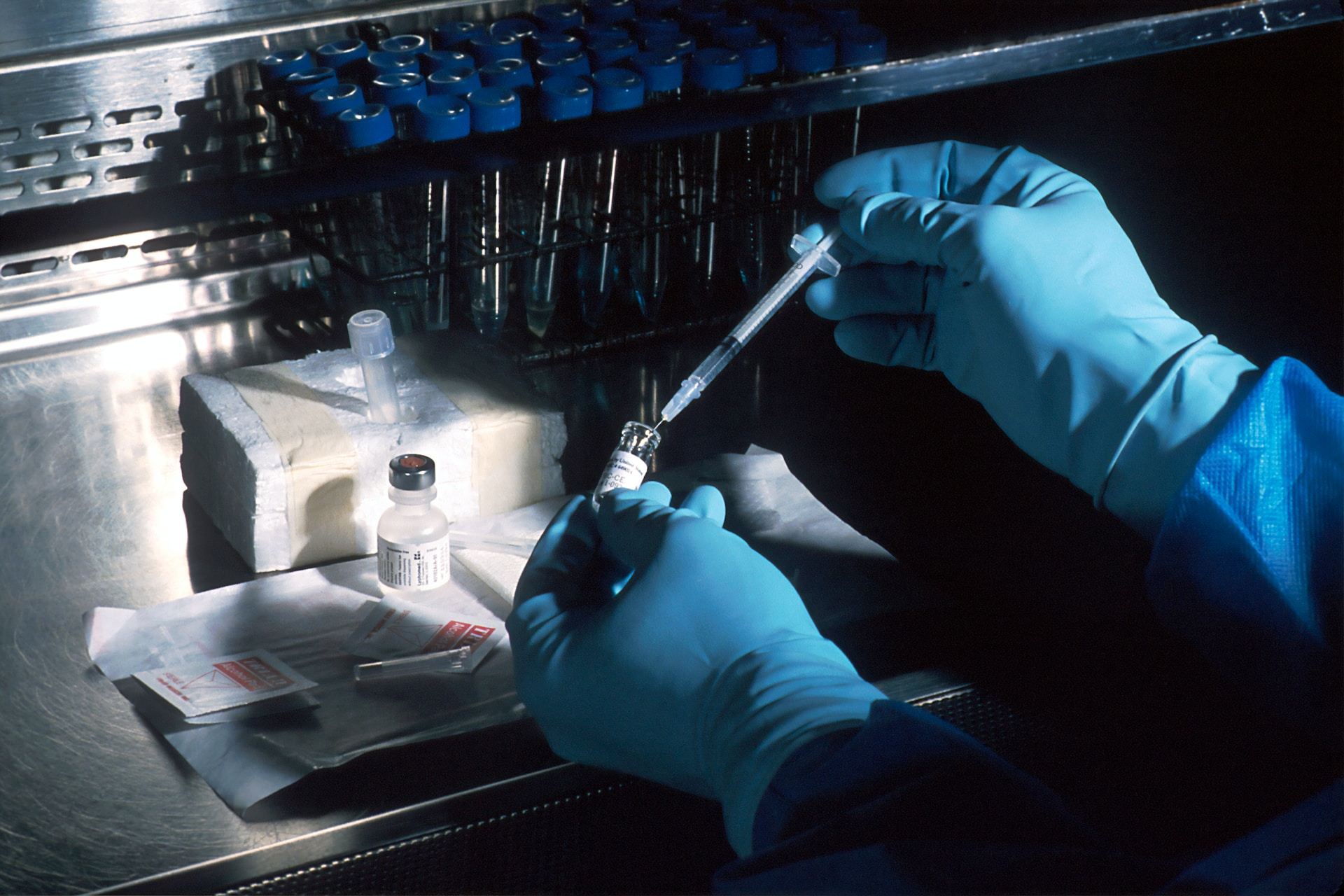 A clinical research practitioner working with a vaccine, ready to administer to a trial participant.