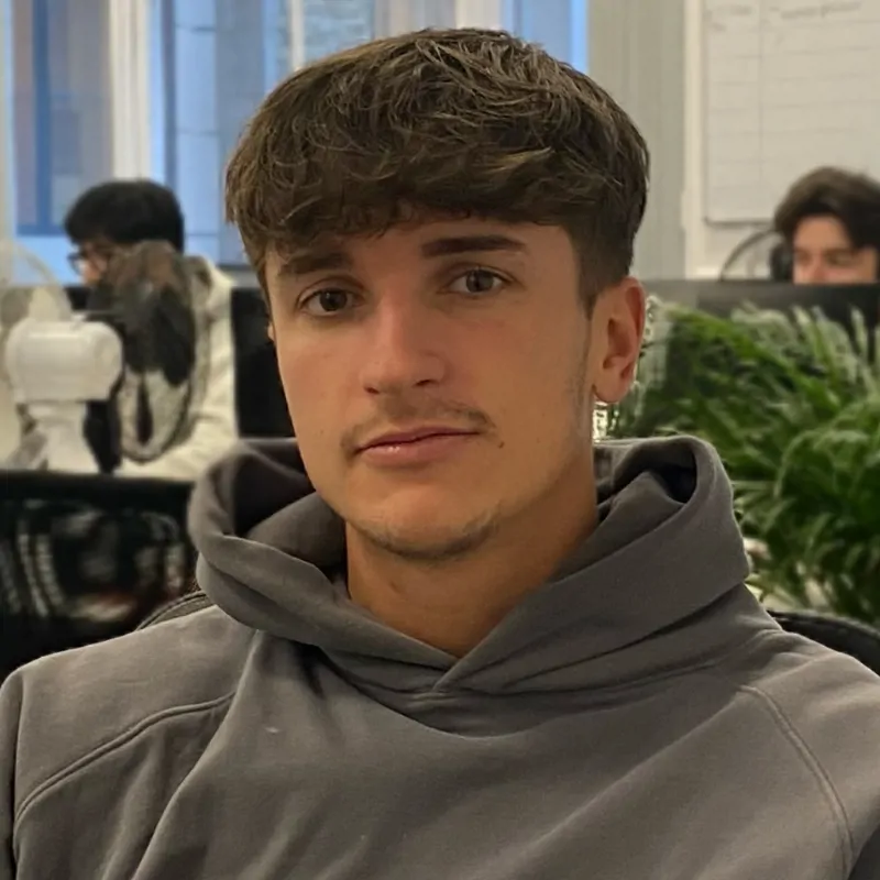 A young man sitting down in an office looking at the camera. He is Ryan Knight, a Team Leader.