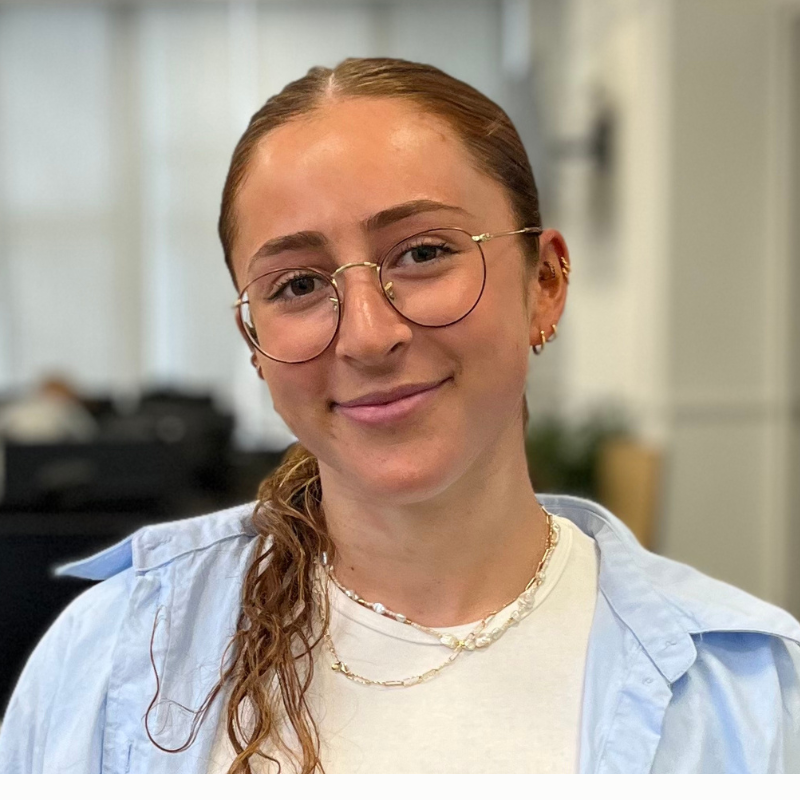 A young woman in an office smiling at the camera. She is Olivia Bloom, Senior Consultant.