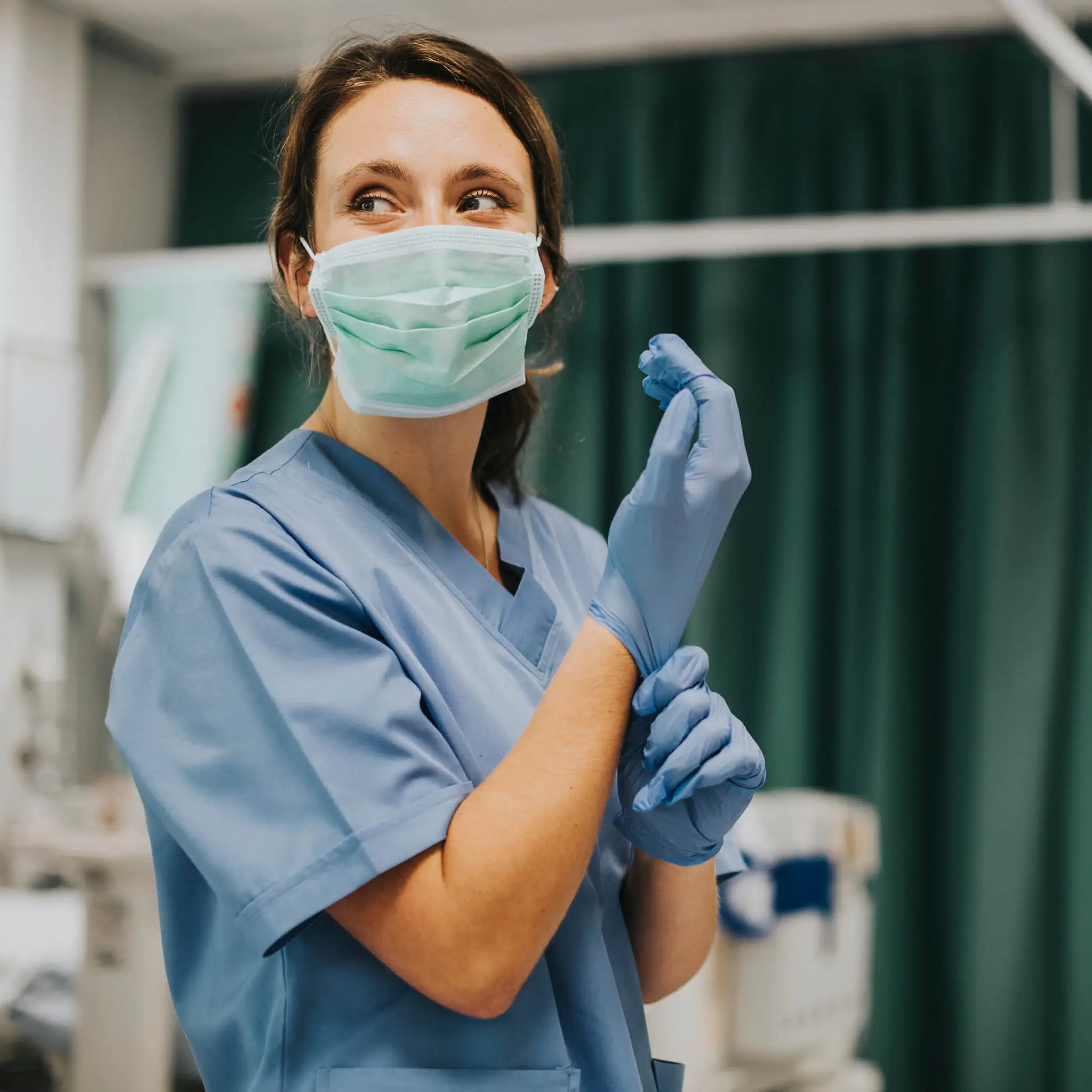 nurse-dressed-in-scrubs-putting-on-surgical-gloves