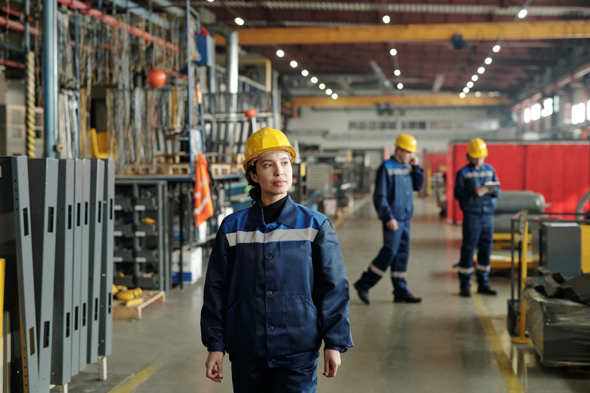 serious-confident-young-female-factory-foreman-in-hardhat-walking-along-compressor-plant-shop-and-controlling-work-of-employees
