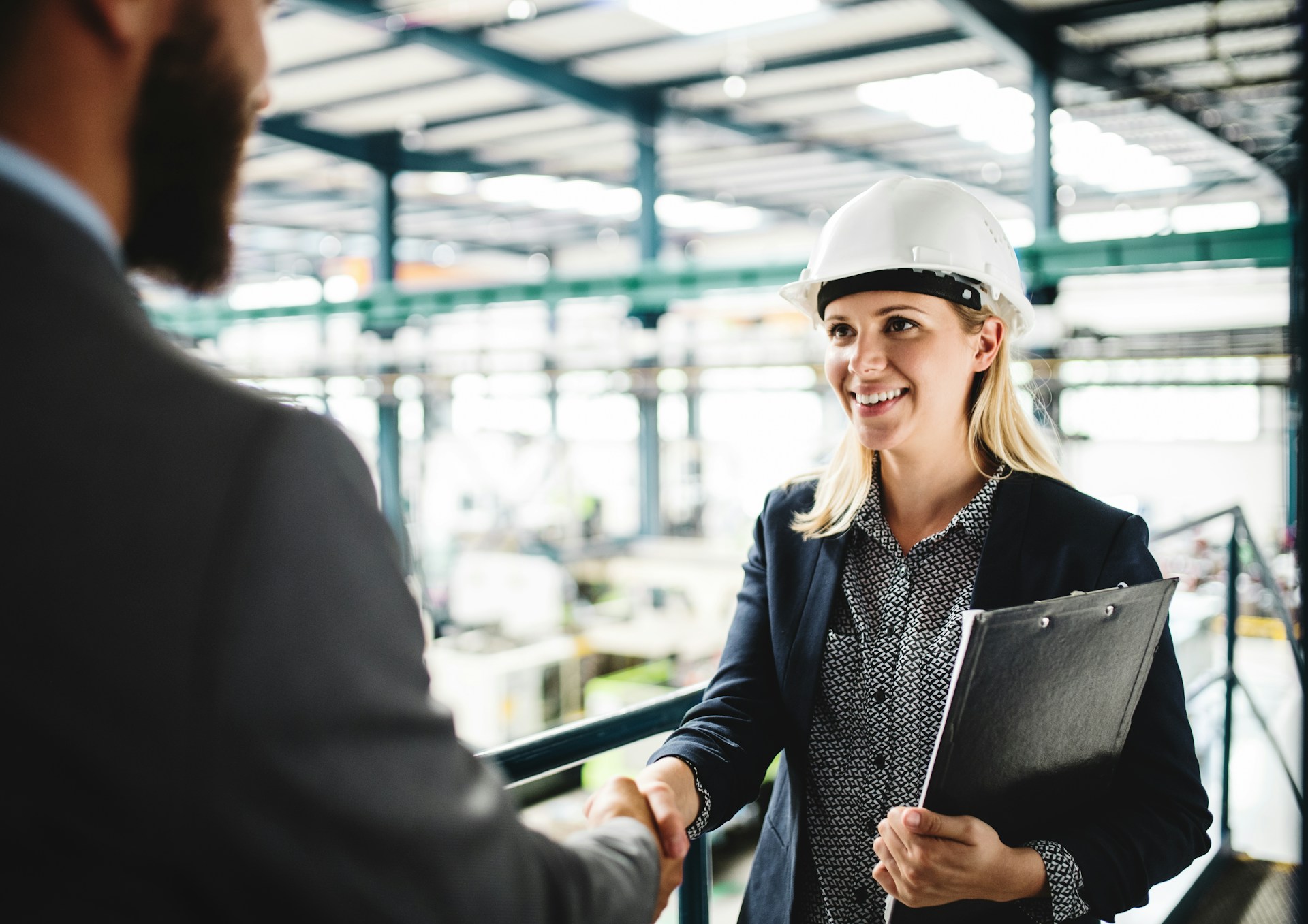 a-portrait-of-an-industrial-woman-and-unrecognizable-man-engineer-in-a-factory-shaking-hands-