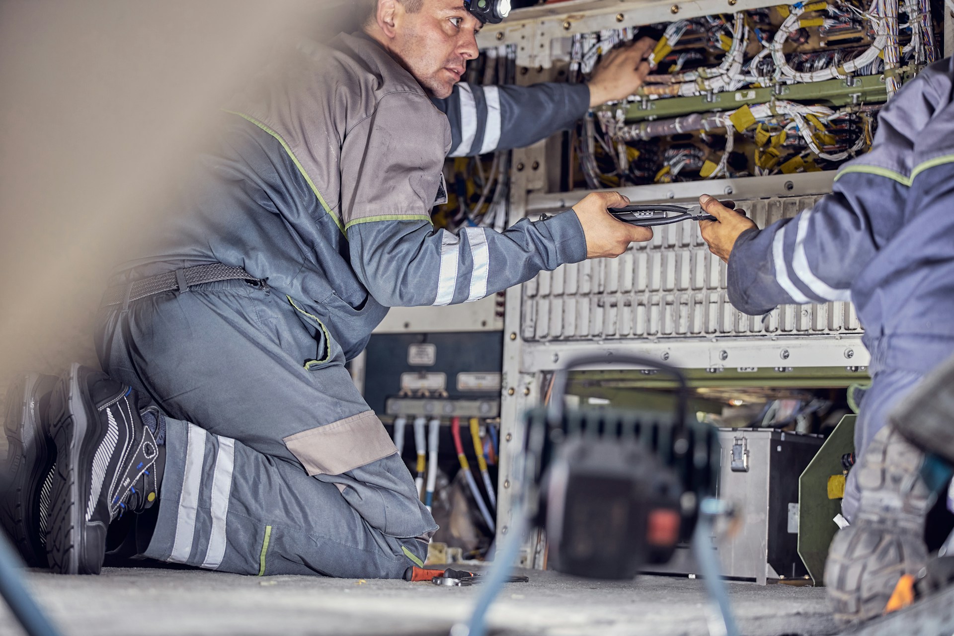 cropped-head-portrait-of-employees-wearing-uniform-using-tools-and-aviation-equipments-are-working-on-the-wiring-inside-the-cabin