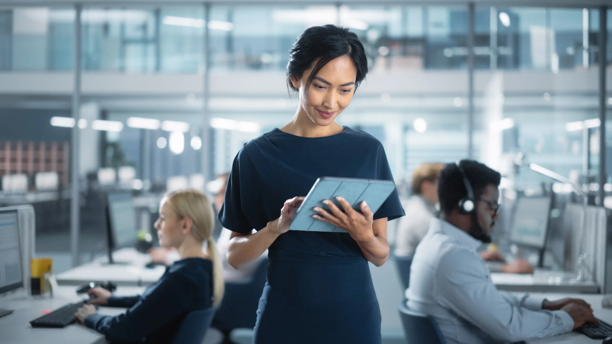 Businesswoman in Stylish Dress Using Tablet Computer, Standing in Modern Diverse Office Working on Financial, Business and Marketing Projects. 