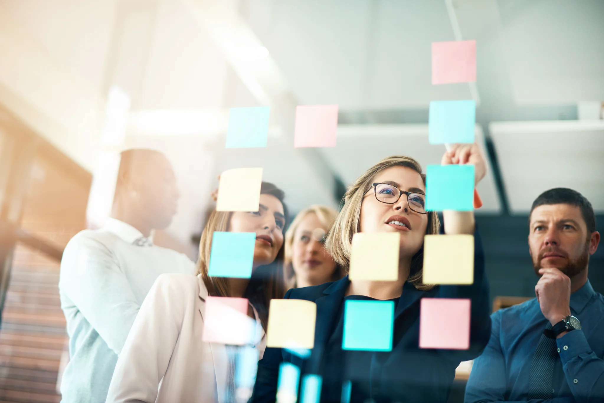Planning, innovation and vision business meeting in a modern office, working on a business marketing strategy. Group, team or staff discussing with sticky notes a schedule for future project 