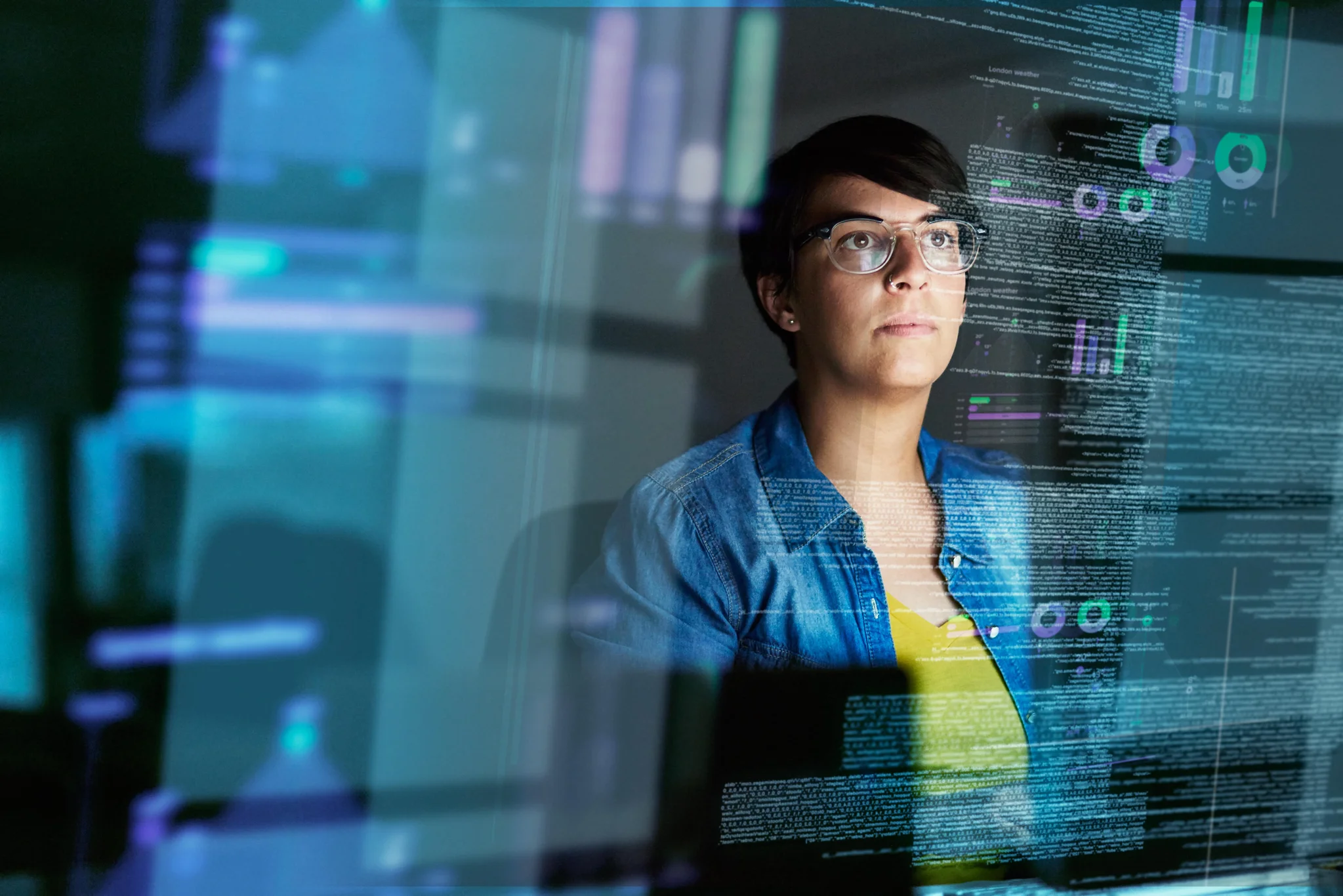 Woman with short black hair observing a group of graphs on a holographic screen