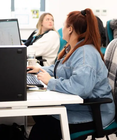 Two women sat at their desked looking away