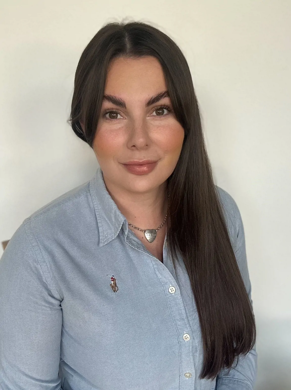 Woman with dark hair and blue shirt smiling for phot