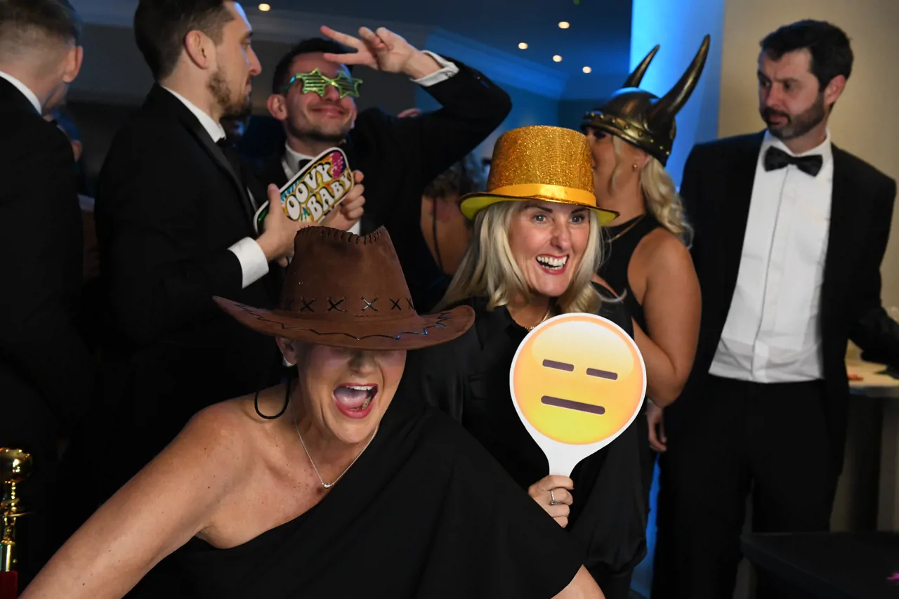 Group in a photobooth wearing props and posing