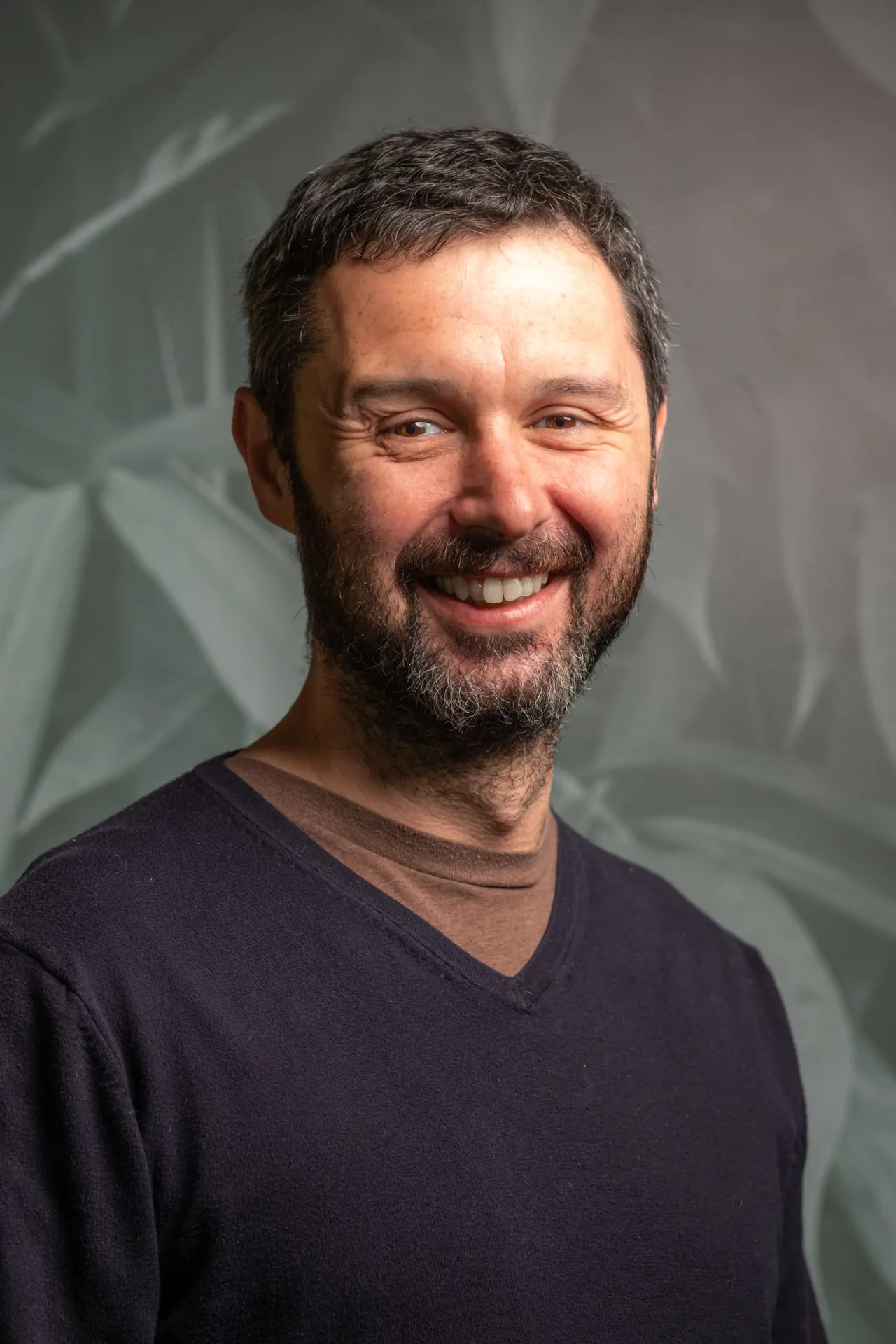 Man wearing v neck jumper smiling for headshot photo