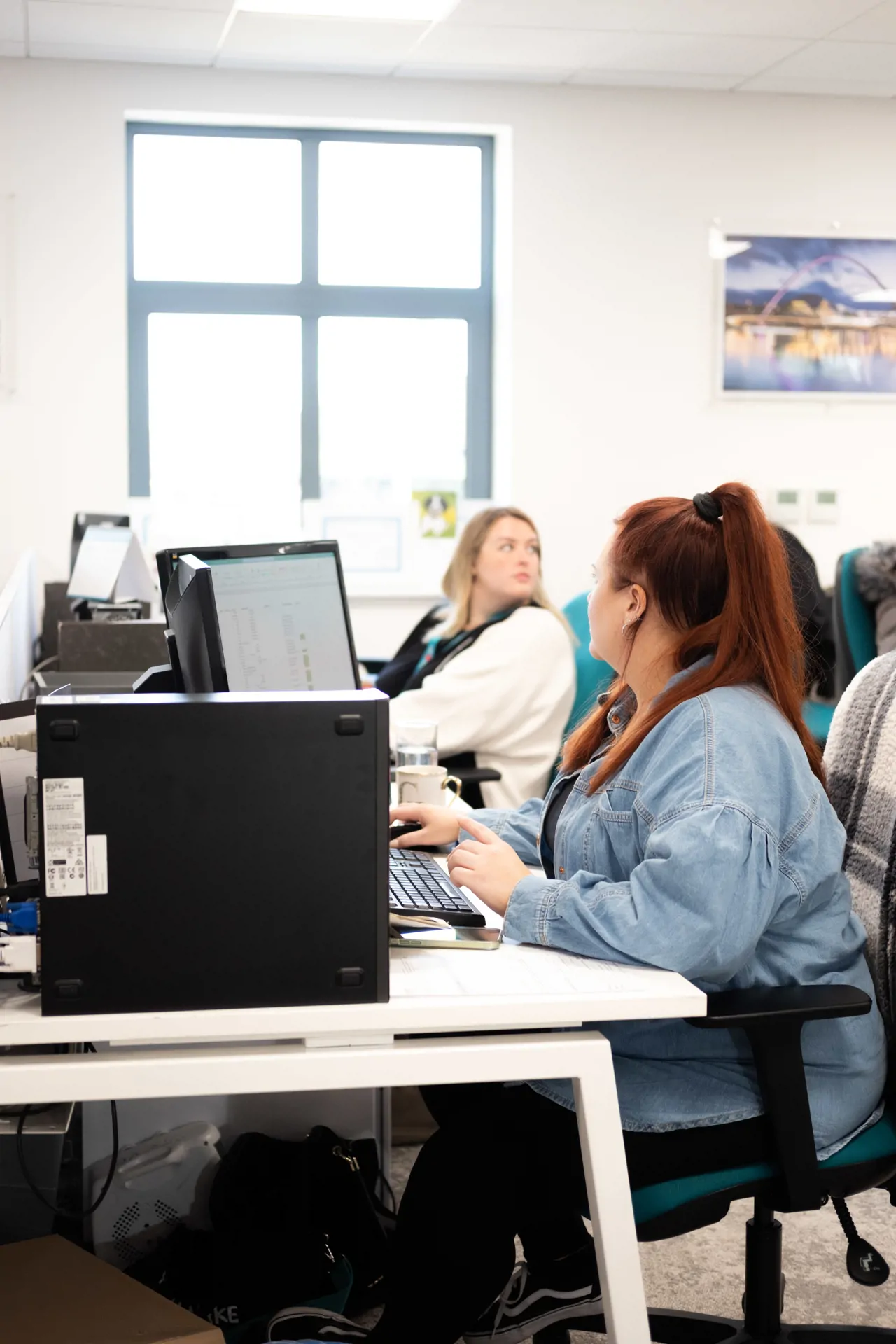 Two women sat at their desked looking away