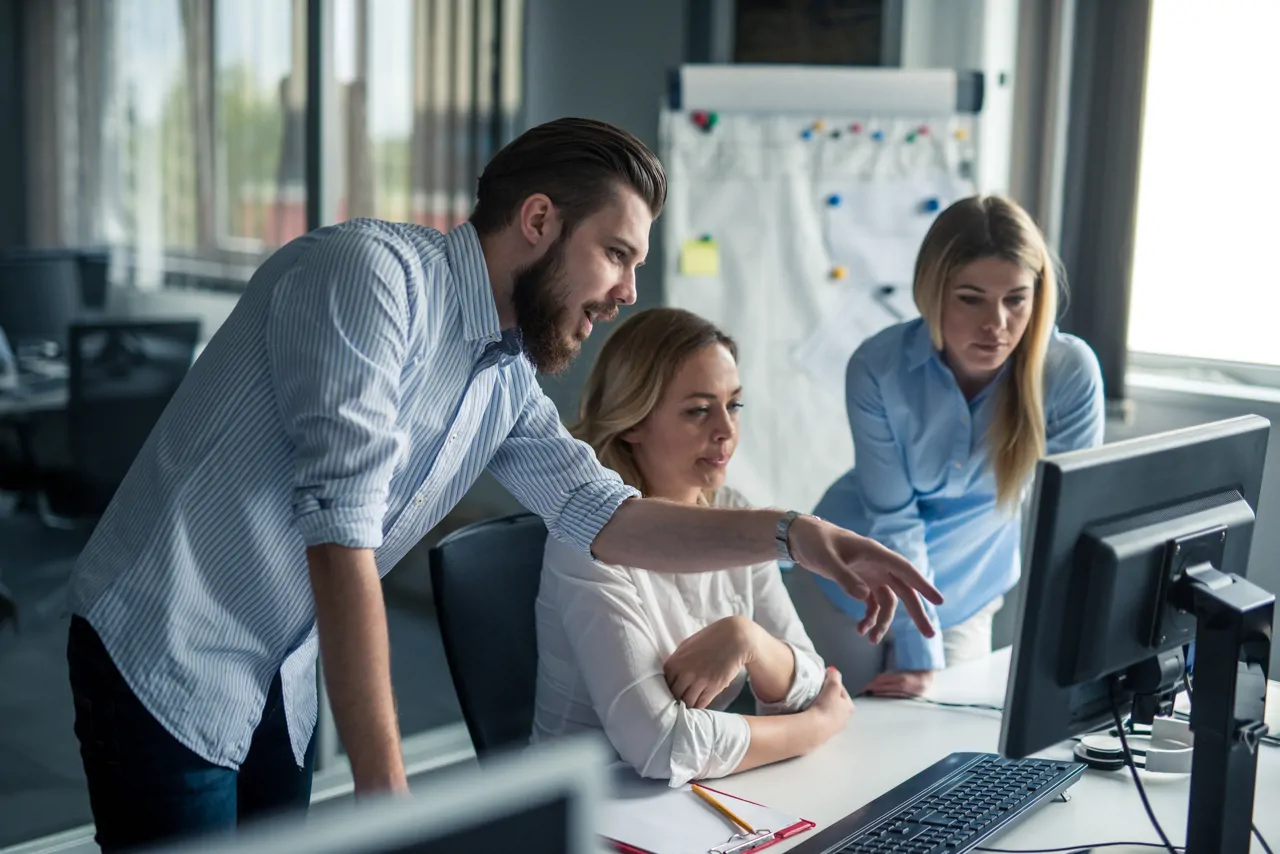 Three people standing around a computer