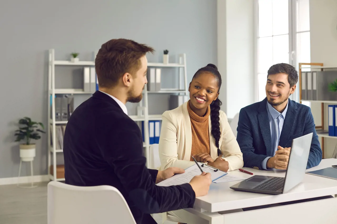 Three people sat around a laptop smiling