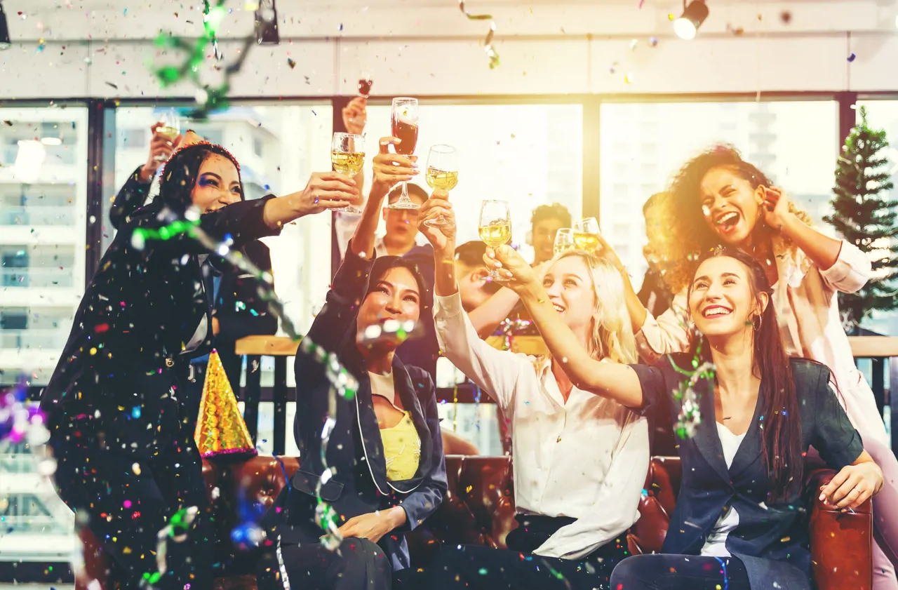 Group celebrating with raised glasses and confetti