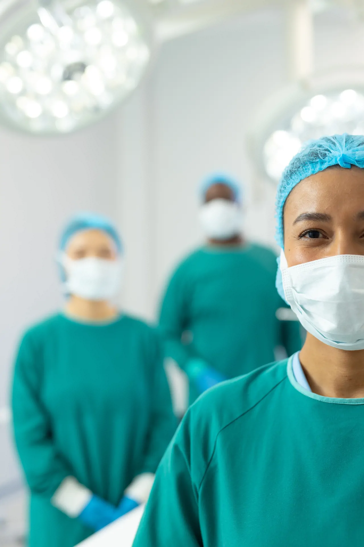 Theatre nurses wearing masks and scrubs assisting during surgery.