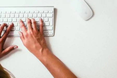 hands typing on a wireless keyboard