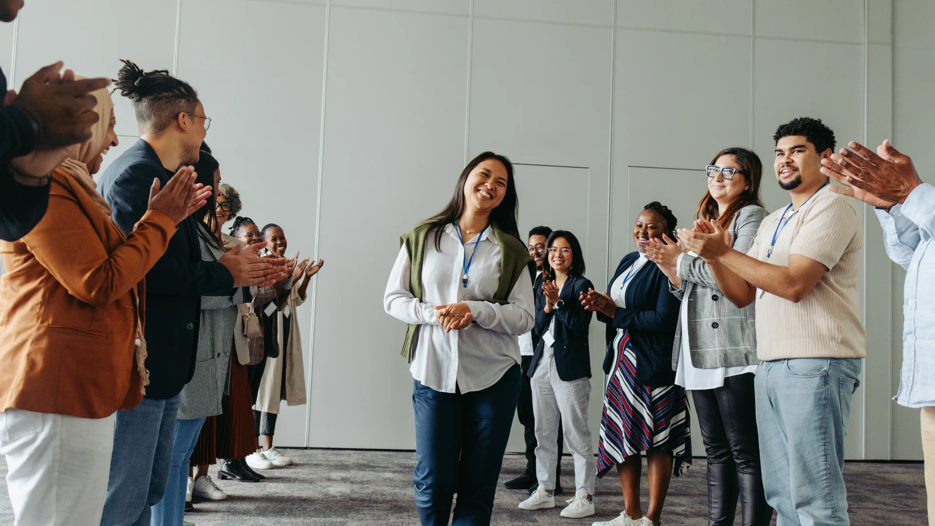Group of employees clapping and smiling at a business conference, celebrating an award