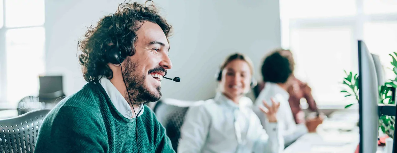 A smiling male call handler in an office