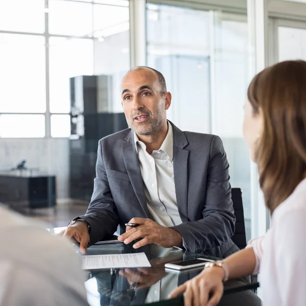 Corporate banker discussing financial solutions with business clients in a modern office.