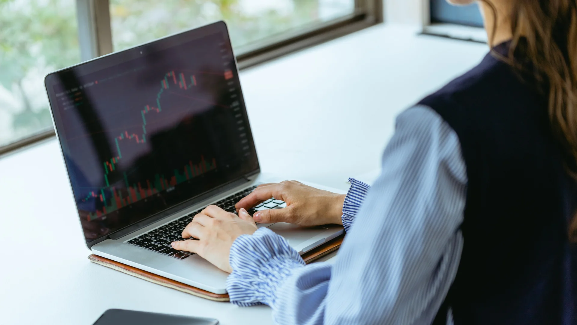 FinTech professional analysing financial data on a laptop in a modern tech office
