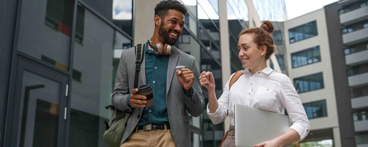 Two professionals fist bumping while walking between office building