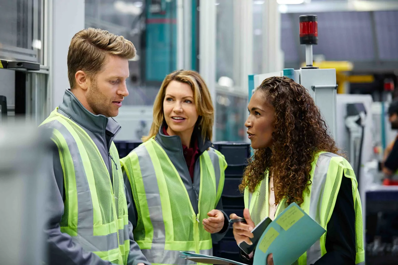 Three warehouse workers in high visibility vests