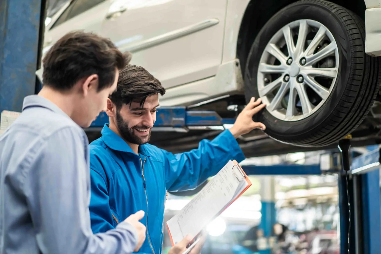 Car mechanic speaking with customer while car is being worked on