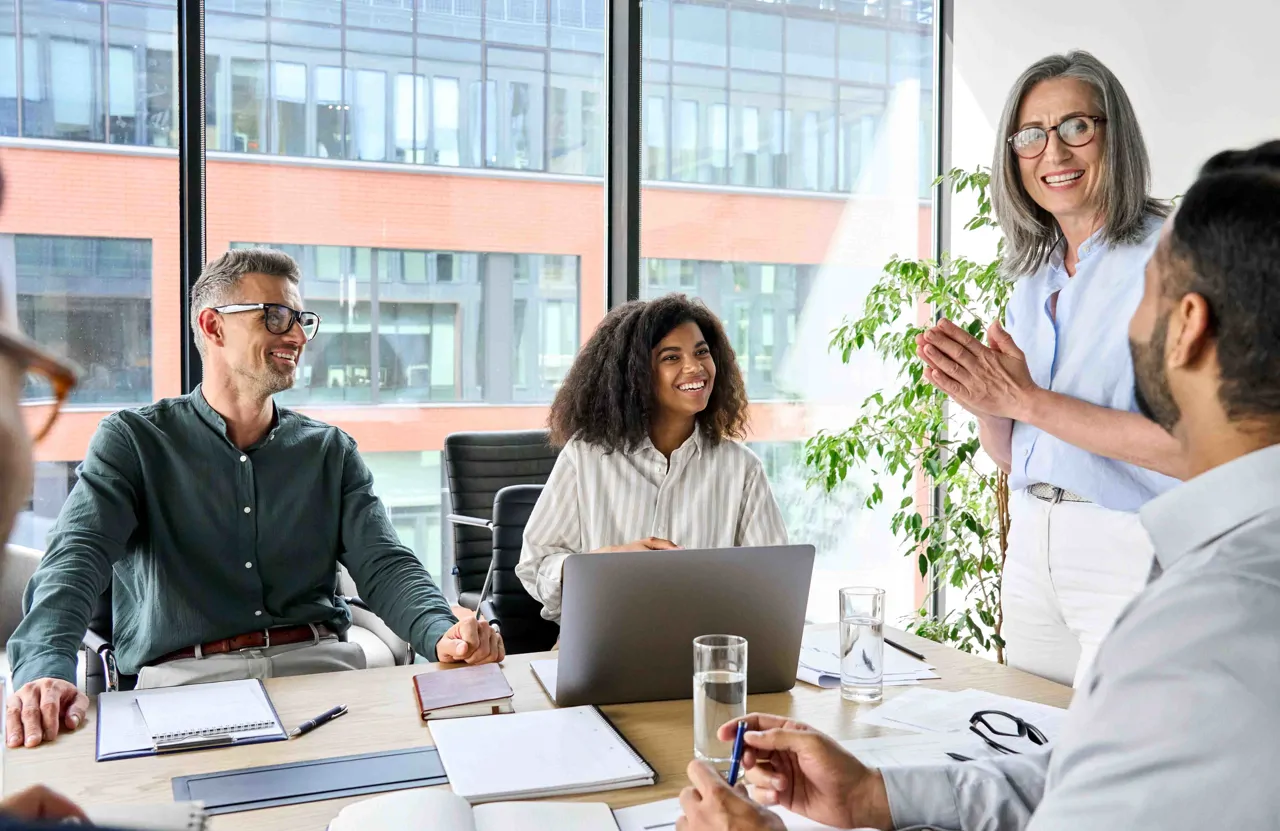 Five people in a meeting smiling