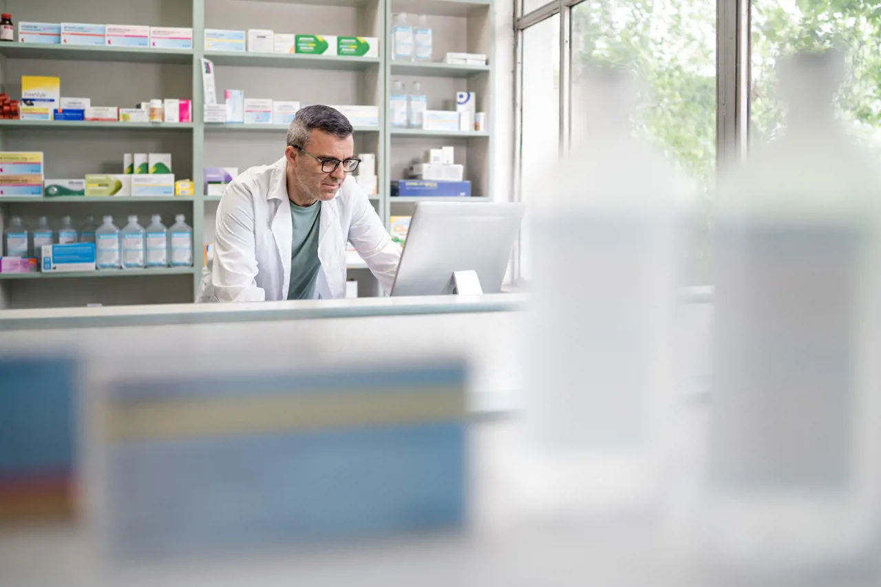 Pharmacist looking at computer screen behind the counter