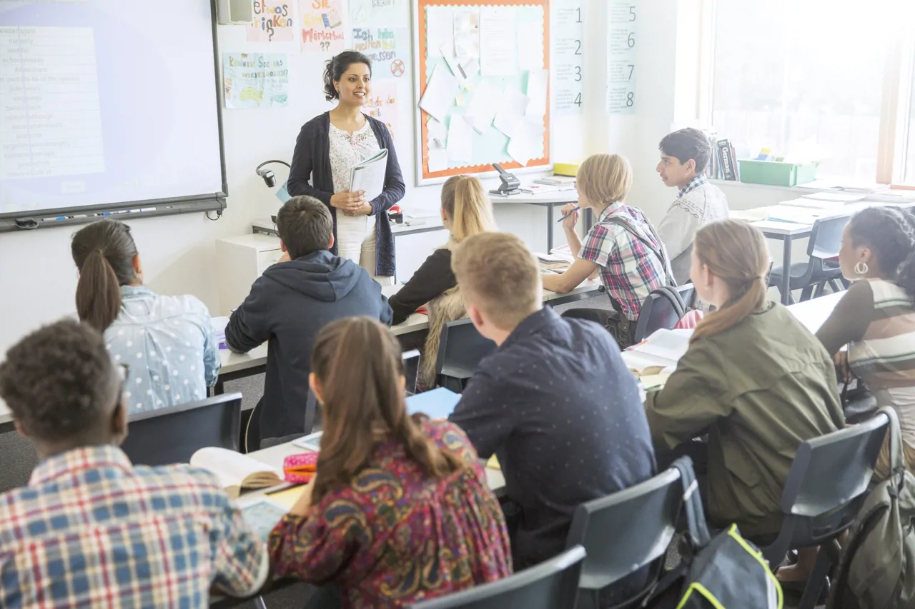 Teacher stood at the whiteboard in a classroom full of students