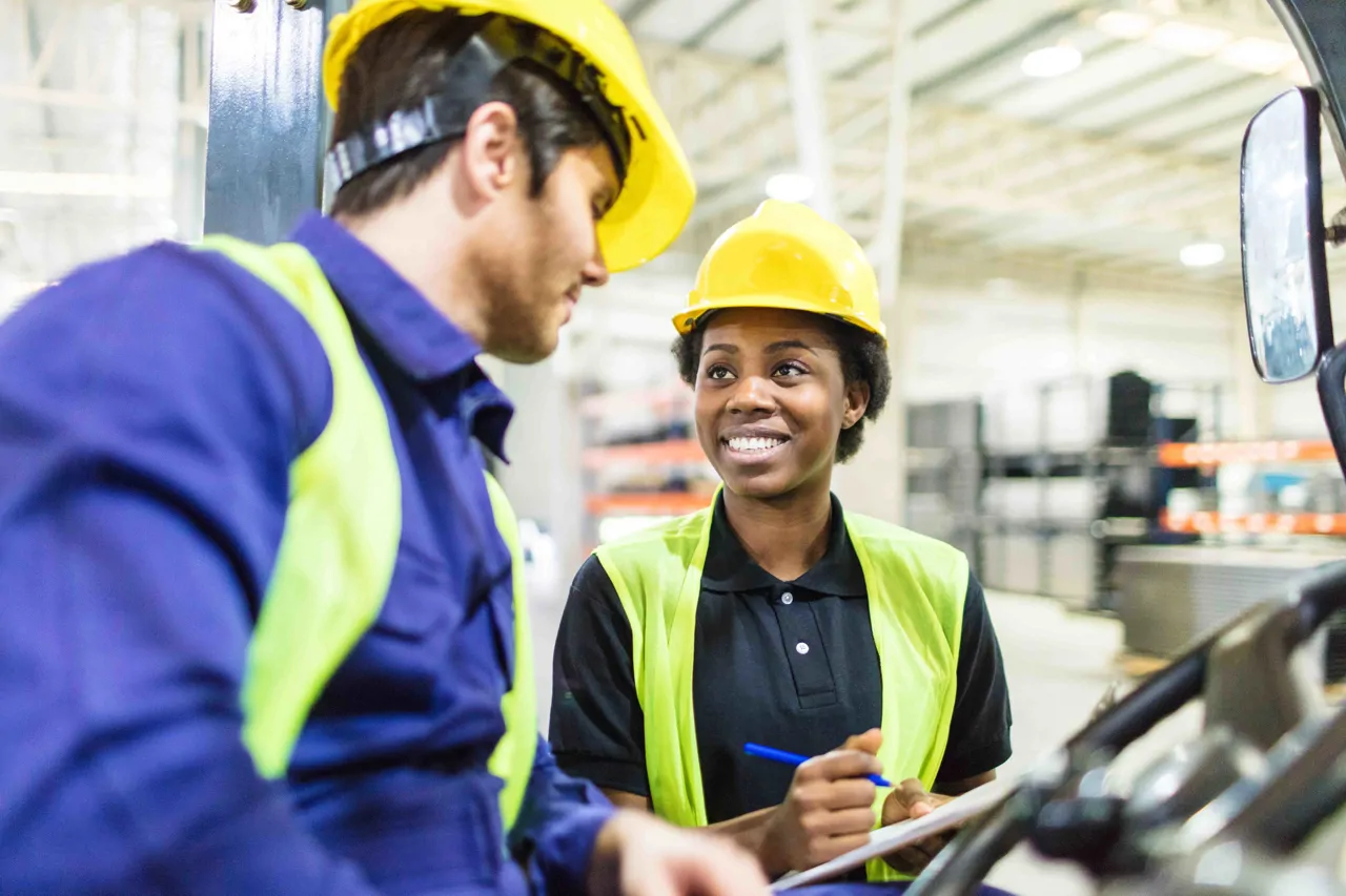 A forklift truck operator talking to a colleague