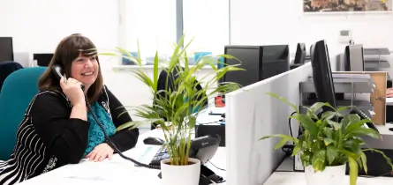 Woman sat at her desk in the office speaking on the phone