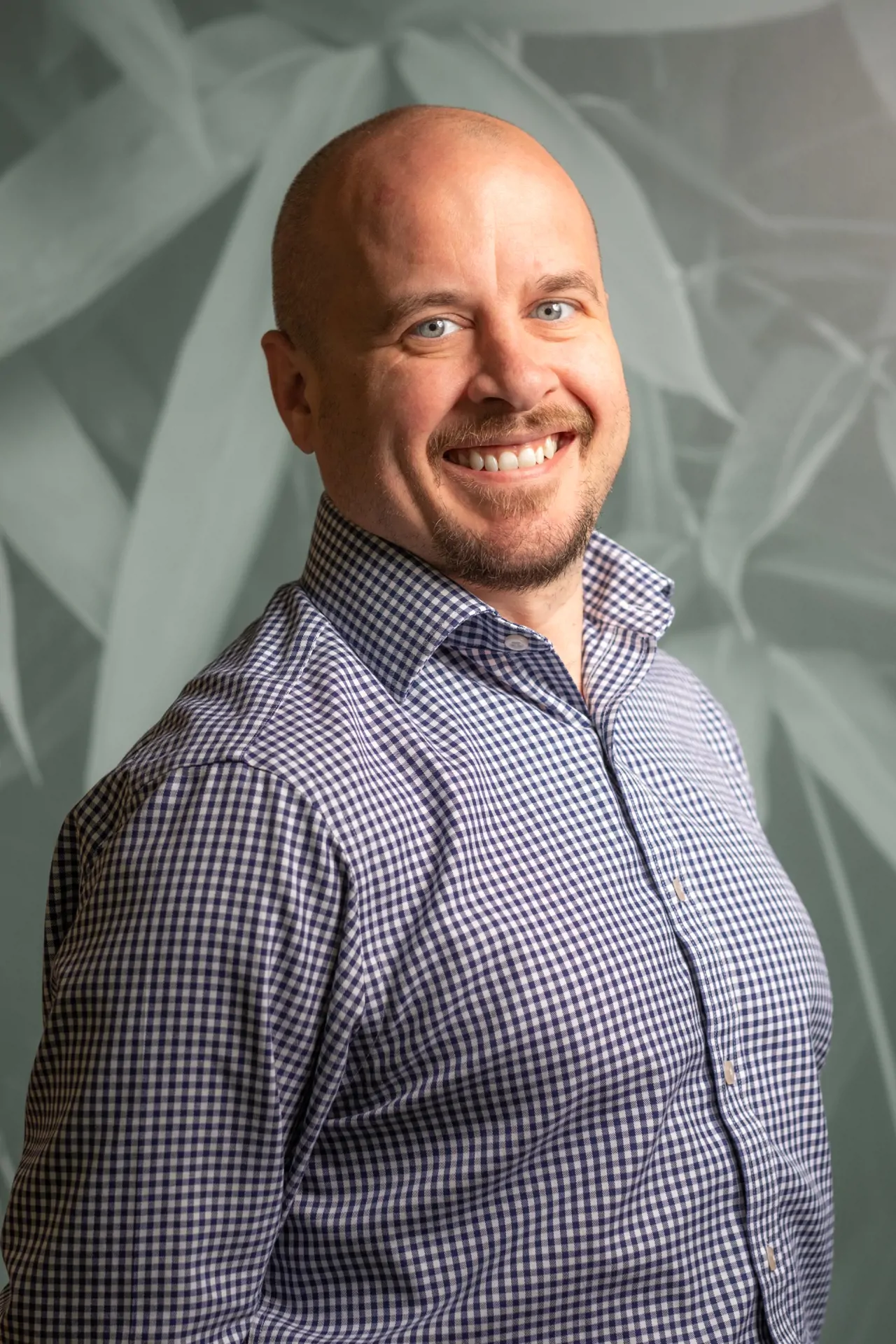 Man in check pattern shirt smiling for headshot photo