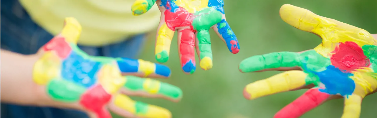 Three young children's hands with paint on them