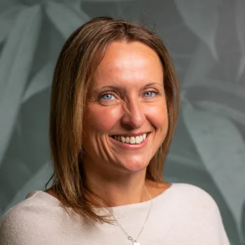 Headshot photograph of woman smiling in cream shirt