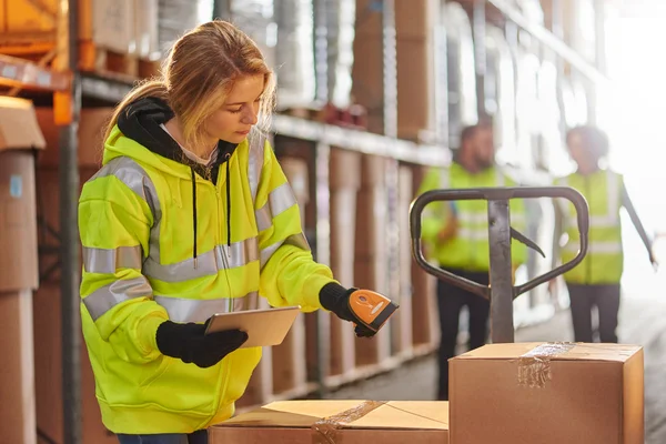 Warehouse operative in hi-vis jacket scanning boxes 