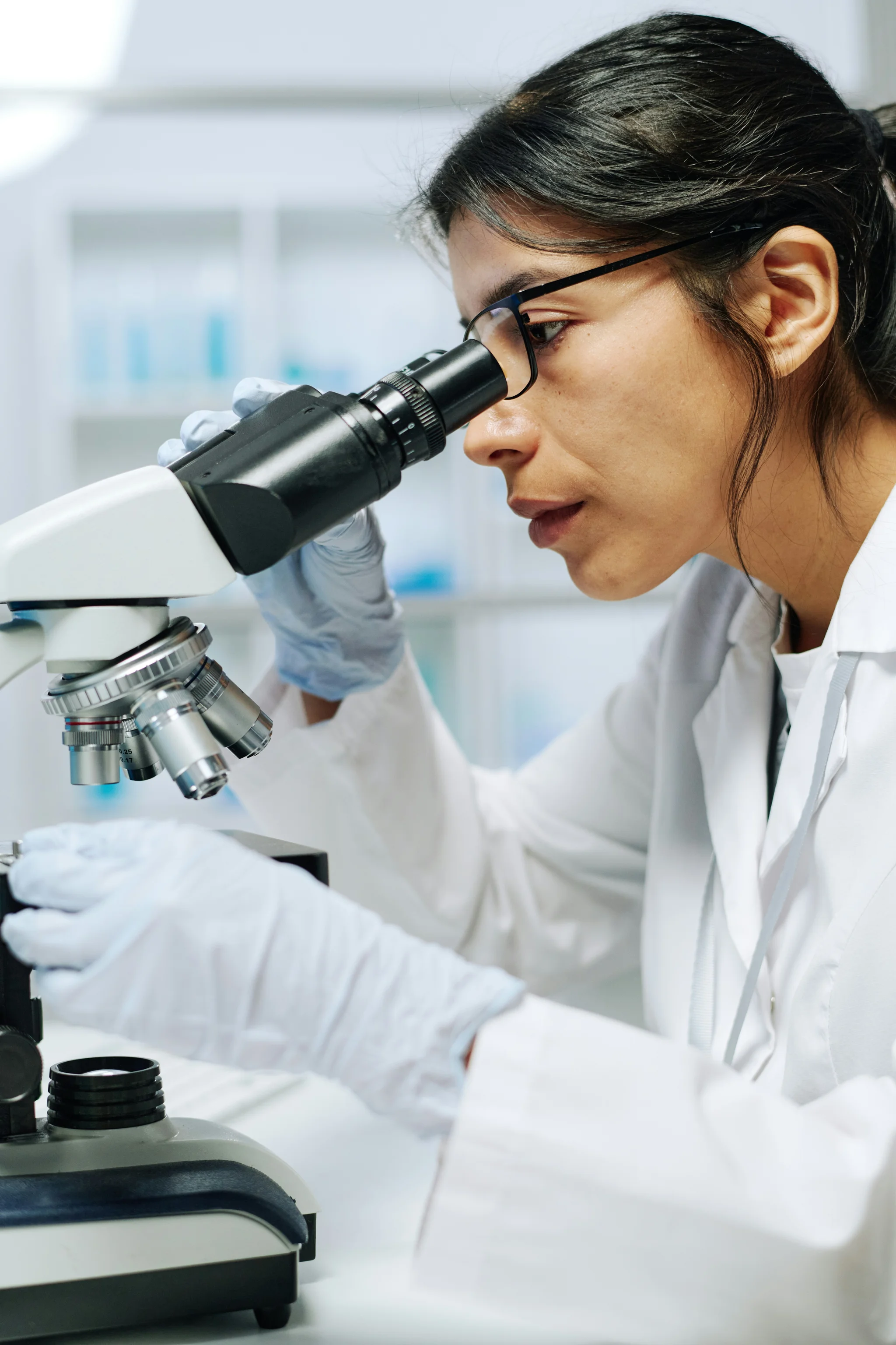 Woman looking through a microscope with glasses