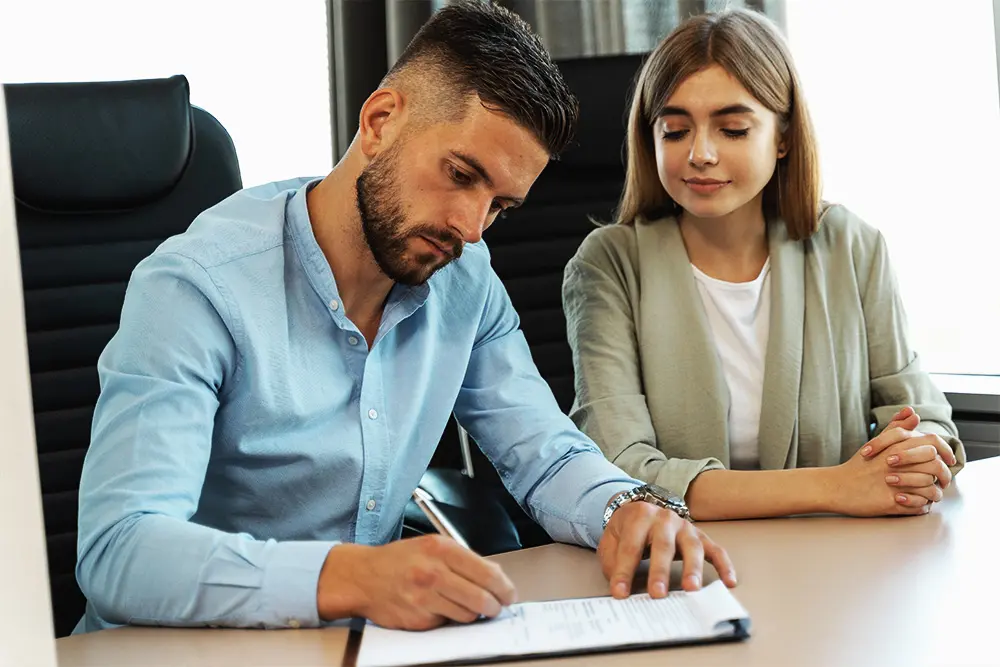 man and woman sat at table training and reviewing paperwork