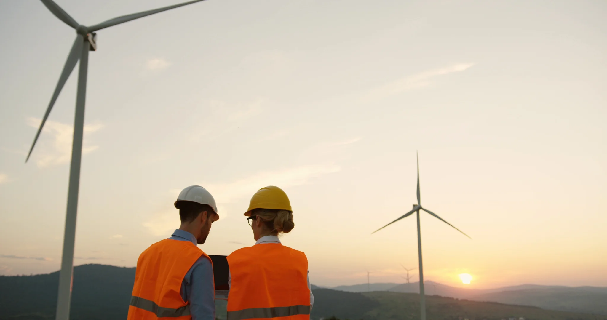 two people standing next to wind power energy