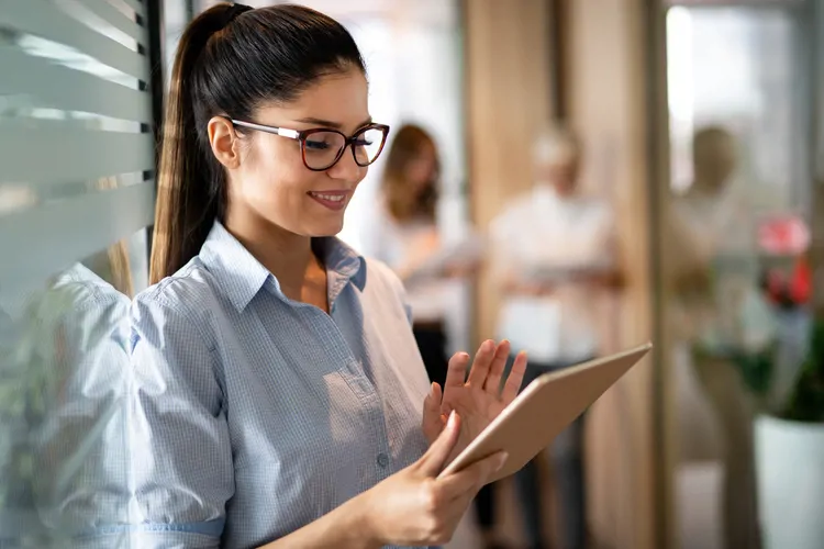 Young happy business woman working with tablet in corporate office