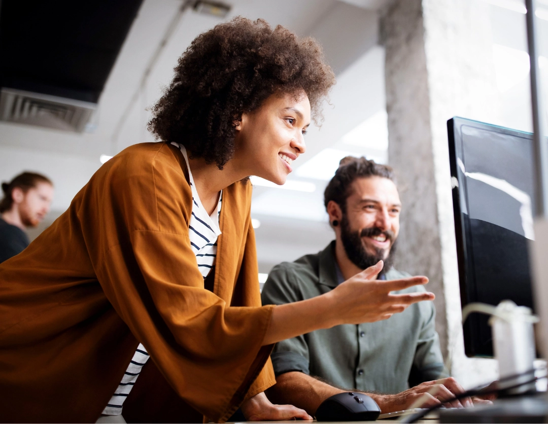 A young man and woman smiling at a computer screen