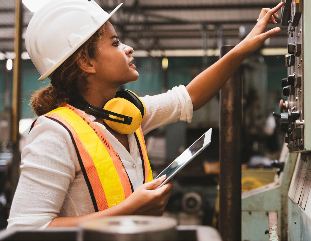 A female construction worker touching a panel of switches and buttons