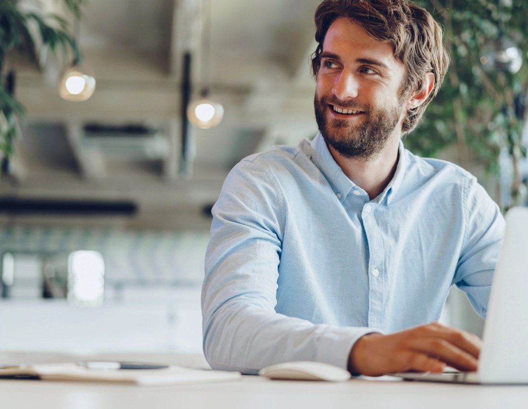 A man wearing a blue shirt sat in front of a laptop