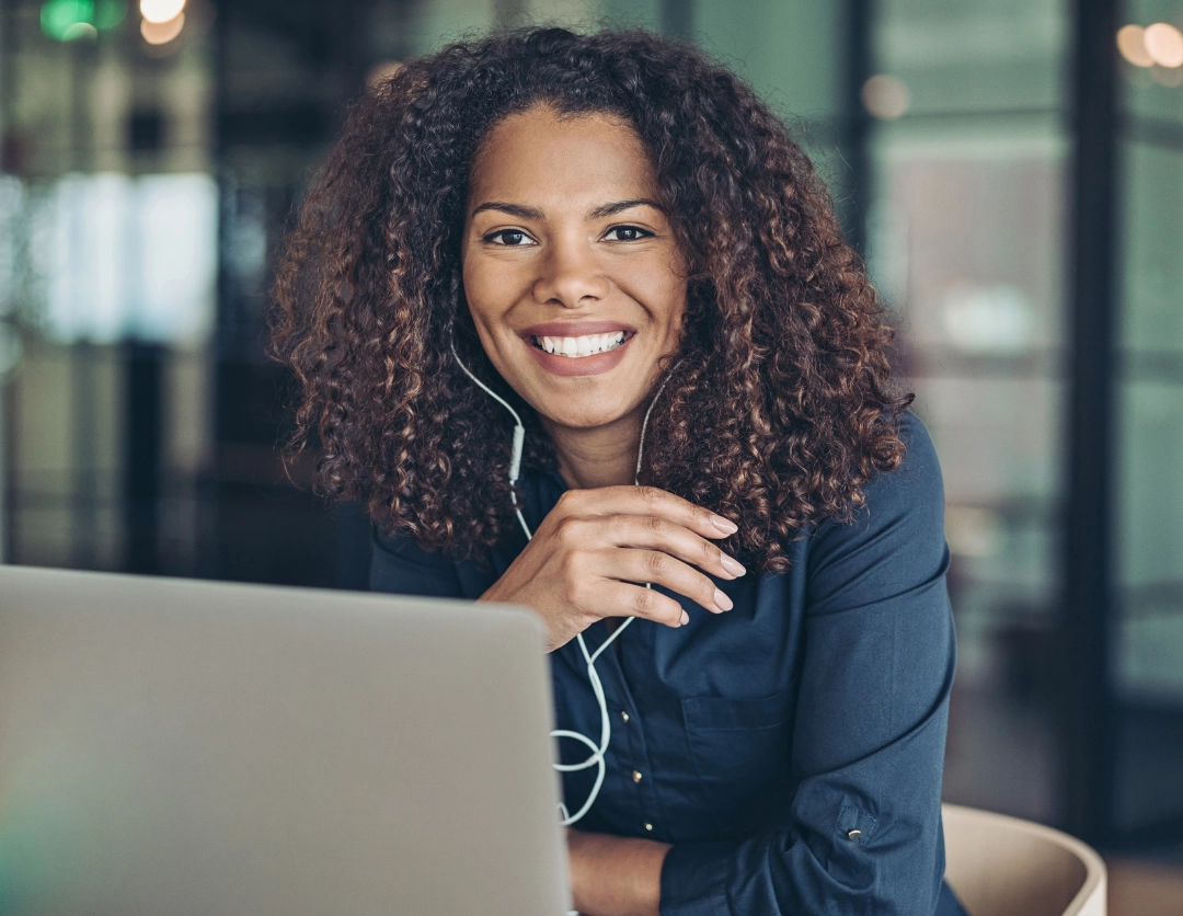 A women wearing headphones sat in front of a laptop