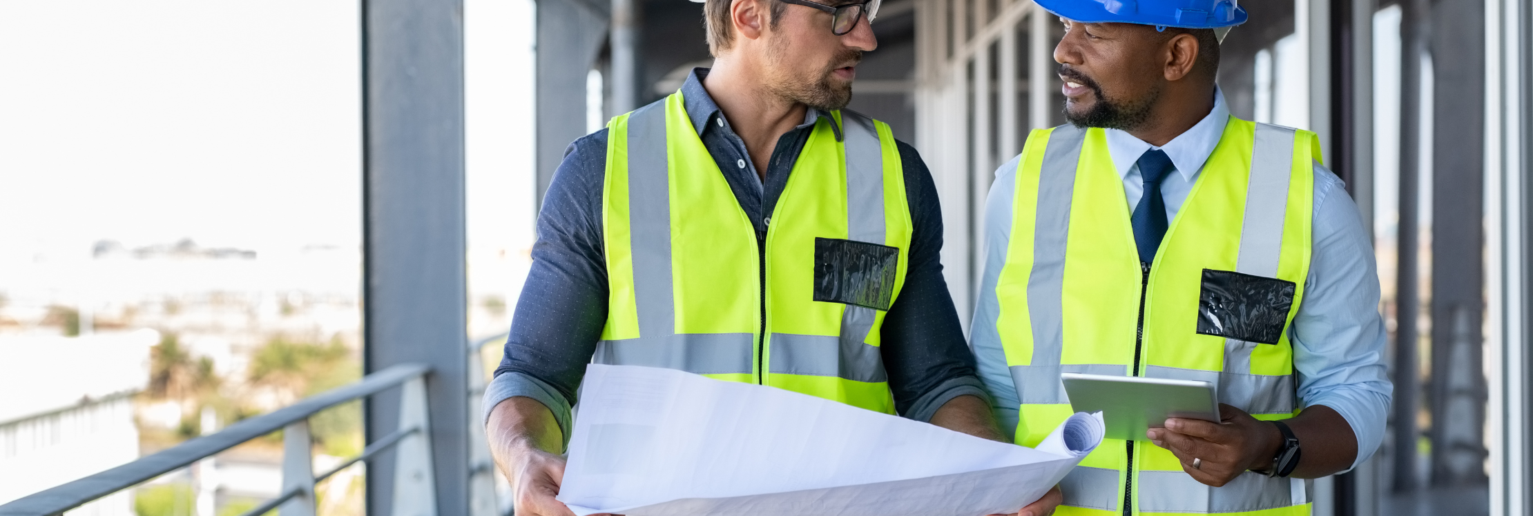 Two workers holding building plans